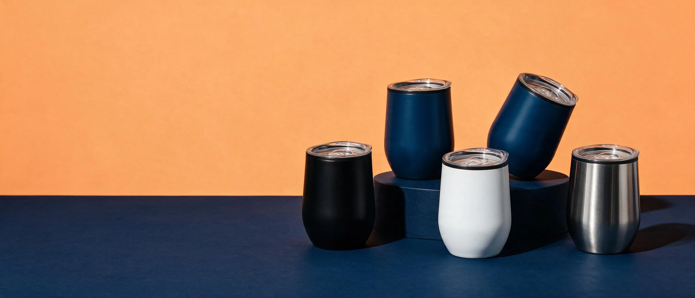 Termos Laska negro, azules, blanco y plata sobre fondo naranja y azul marino